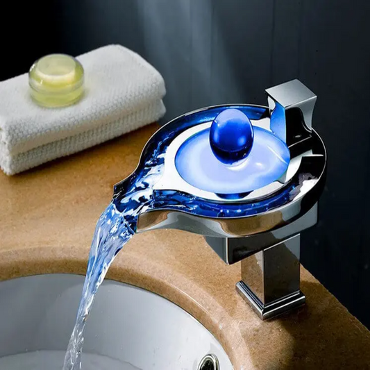 Chrome faucet with blue light pouring water into a sink, with a towel and soap in the background.